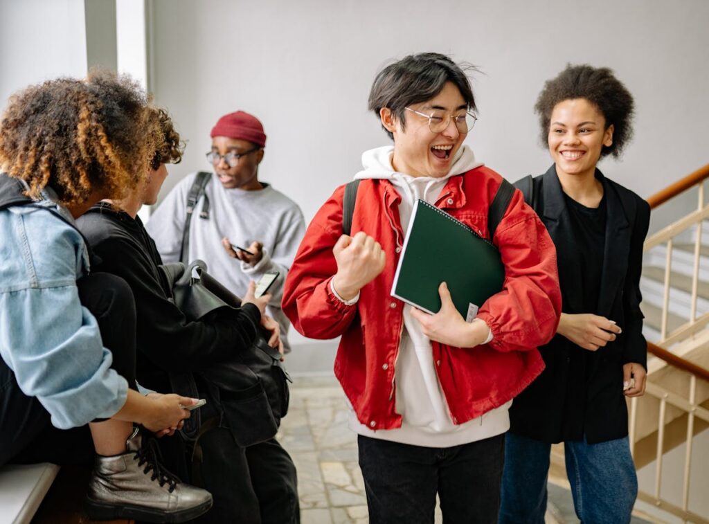 A group of diverse college students happily interacting indoors, showcasing friendship and diversity in a university setting.